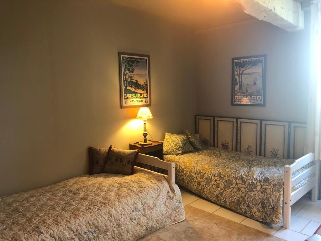 a bedroom with two beds and a lamp on a table at Maison Lamothe in Flamarens