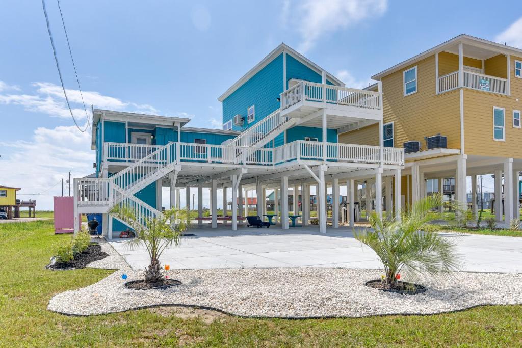 a blue and yellow building with palm trees in front of it at Sunny Freeport Beach House Rental Near Shore in Freeport
