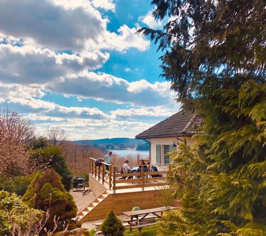 dom z tarasem z ludźmi siedzącymi na nim w obiekcie Villa des Suisses with Jacuzzi & View of Lake des Settons w mieście Moux-en-Morvan