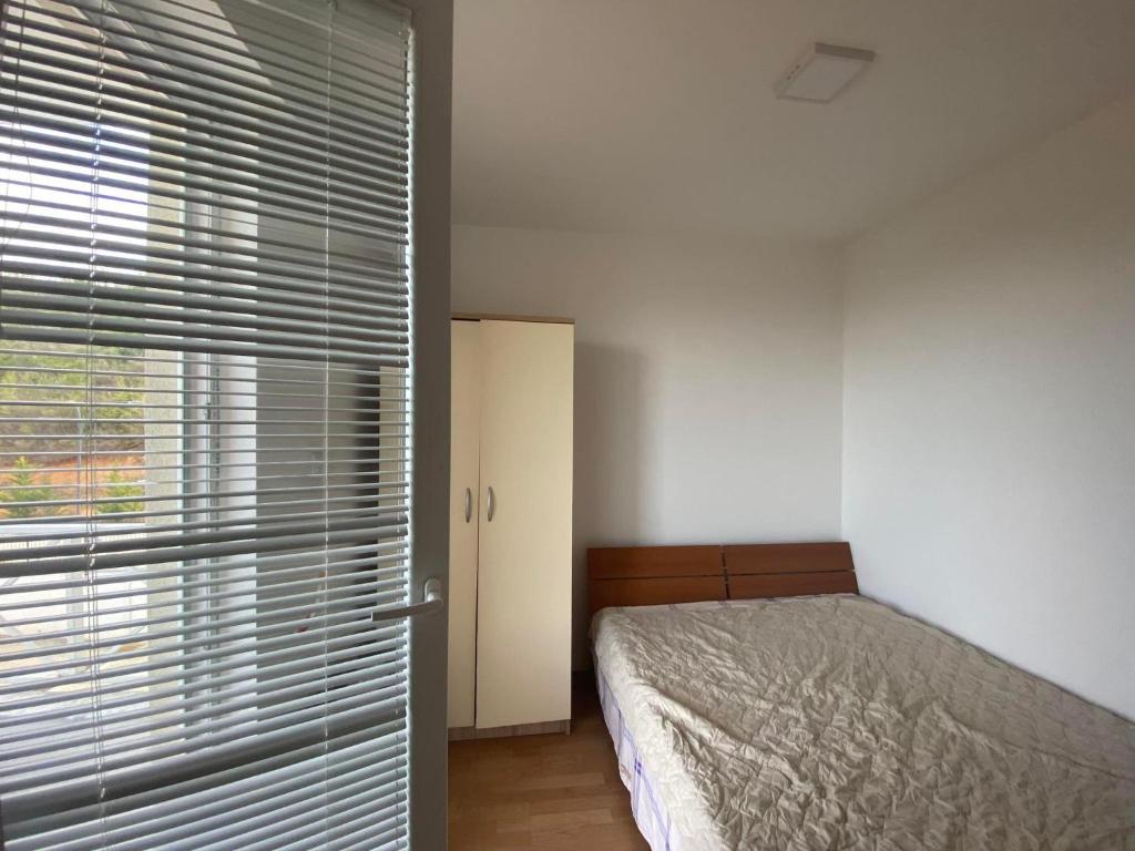 a bedroom with a bed and a window with blinds at City View Condominium in Skopje