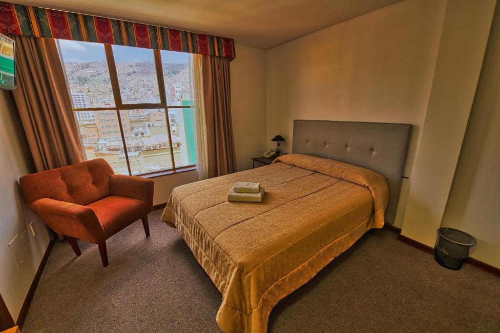 a bedroom with a bed and a chair and a window at Pan American Hotel in La Paz