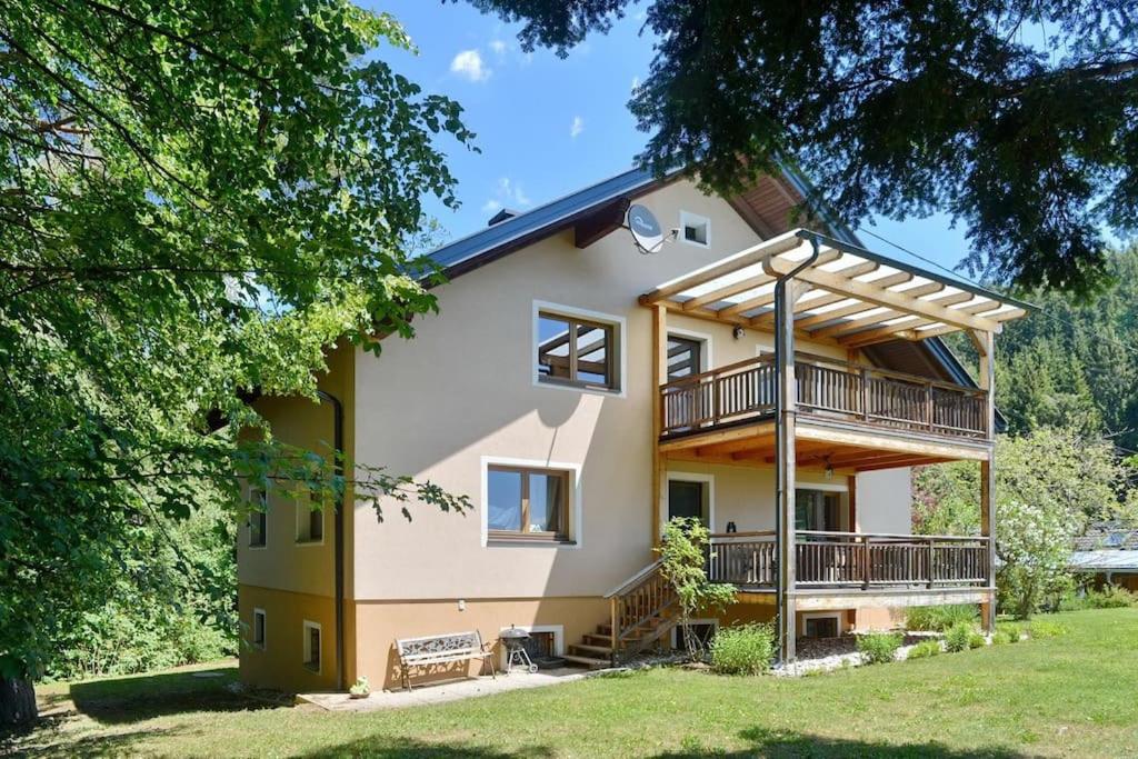 a large house with a balcony and trees at Ferienwohnung Karawankenblick in Bach