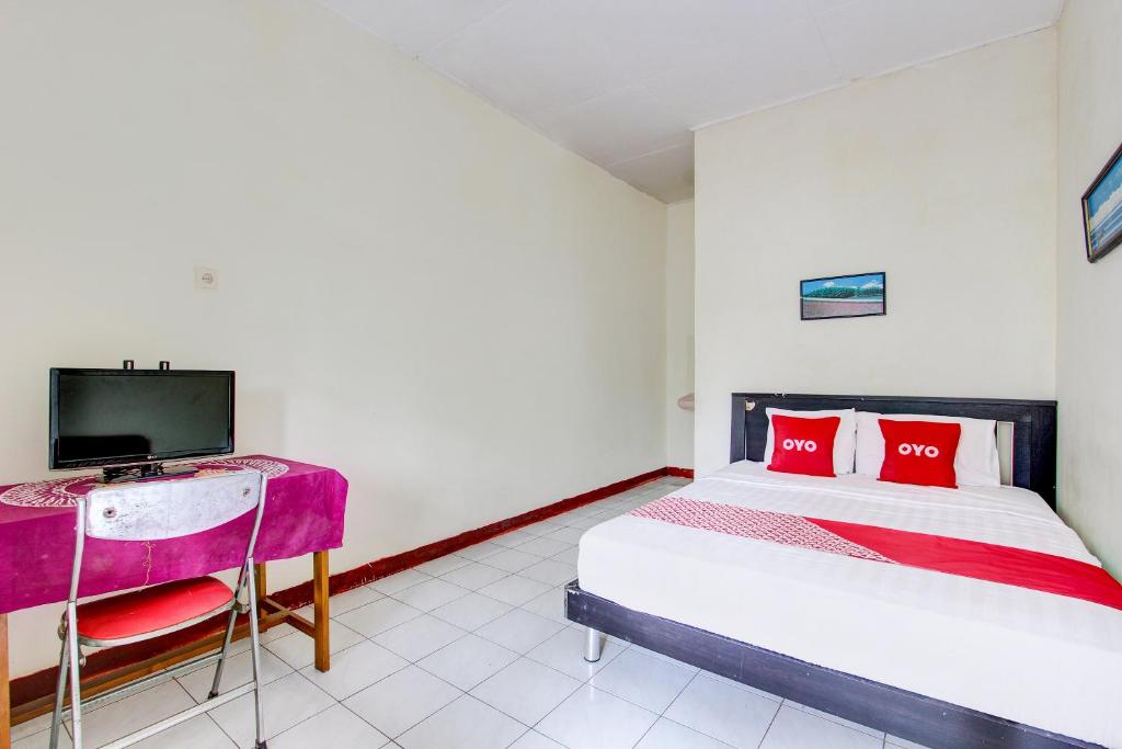 1 dormitorio con 1 cama con almohadas rojas y TV en OYO 92505 Asta Guesthouse en Yogyakarta