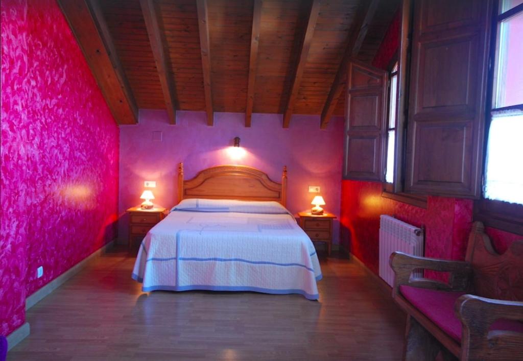 1 dormitorio con paredes rosas y 1 cama con 2 lámparas en Casa de Aldea La Redondiella, en Berodia