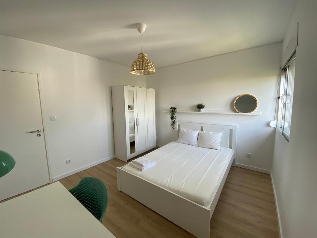 Carcavelos Beach walking distance room in shared apartment في أويراس: غرفة نوم بيضاء مع سرير أبيض ونافذة