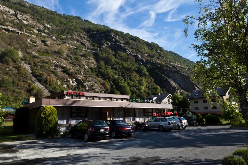 Hotel Garni Simplon في Brigerbad: مبنى فيه سيارات تقف امام جبل