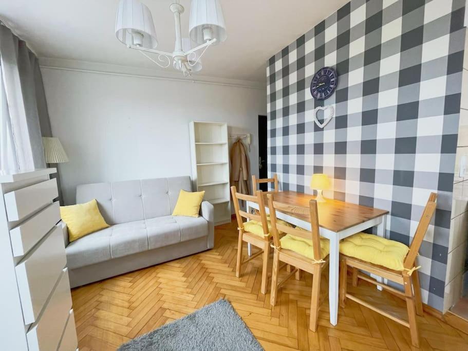 a living room with a table and a couch at Cozy studio apartment Yellow in Gdansk Wrzeszcz in Gdańsk