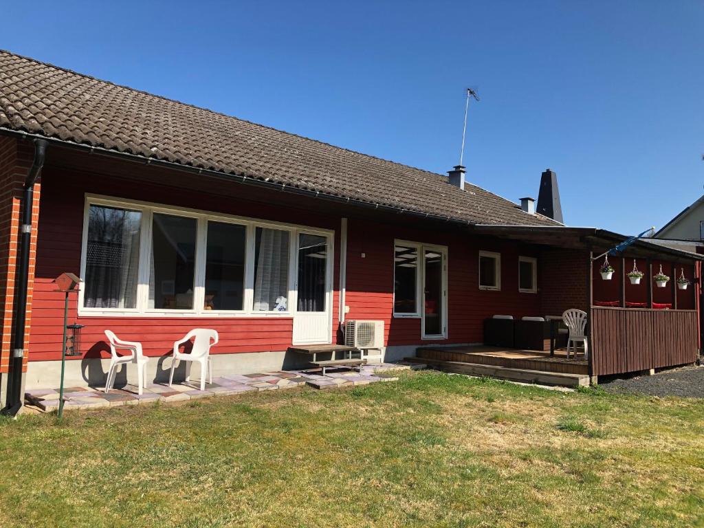 una casa roja con 2 sillas blancas en el porche en Nila's Stuga, en Diö