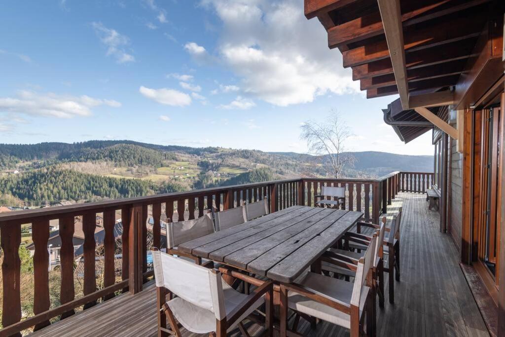 a wooden table and chairs on a deck with a view at Luxueux chalet avec vue sur les pistes et le Hohneck in Le Tholy