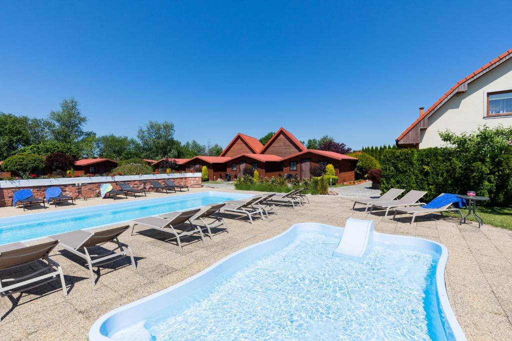 a large swimming pool with chairs and a swimming pool at Dworek Zielińskich-Domki, Apartamenty, Podgrzewany basen, Parking in Rewal