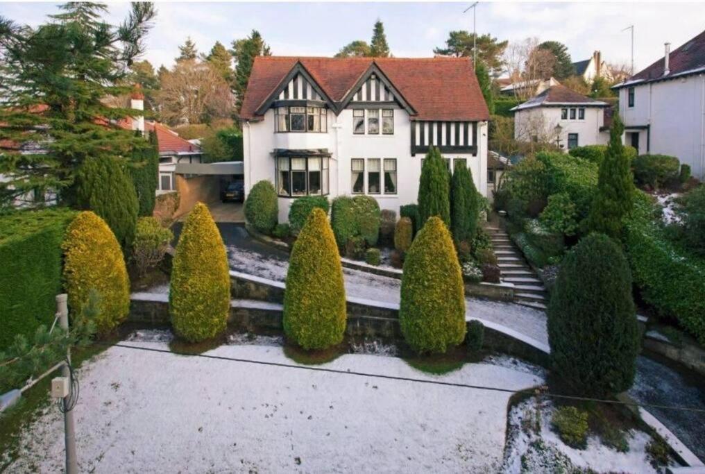 uma grande casa branca com muitas árvores e arbustos em Edwardian Manor near Glasgow City with HEATED POOL & HOT TUB em Giffnock