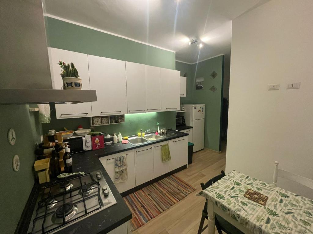 a kitchen with white cabinets and a green wall at Halfway Private Room - Casa all'Italiana in Florence