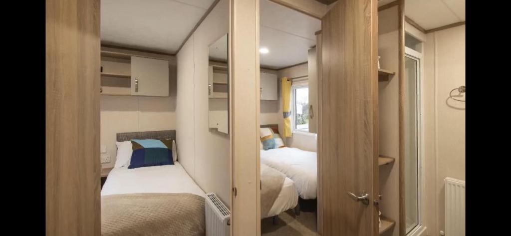 a small room with two beds and a closet at Coopers Beach 3-Bed Caravan Sleeps 8 & Pets Ok in Colchester