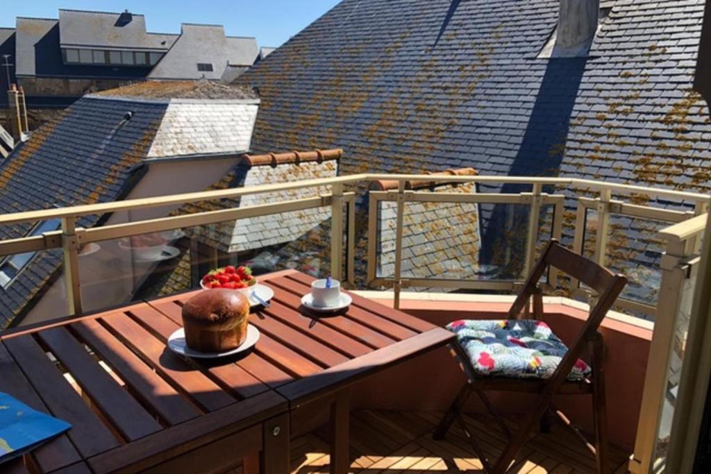 une terrasse en bois avec une table et des chaises sur un balcon dans l'établissement Bright and quiet nest with terrace near beaches, à Saint-Malo