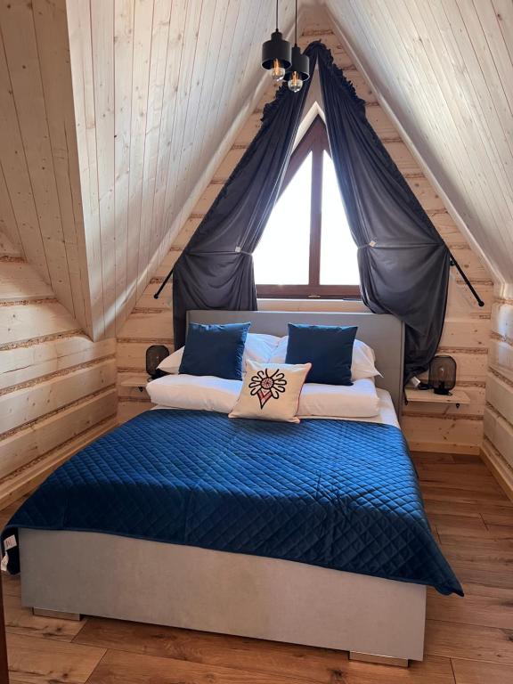 a bedroom with a bed with blue sheets and a window at Liliowa Willa in Zakopane