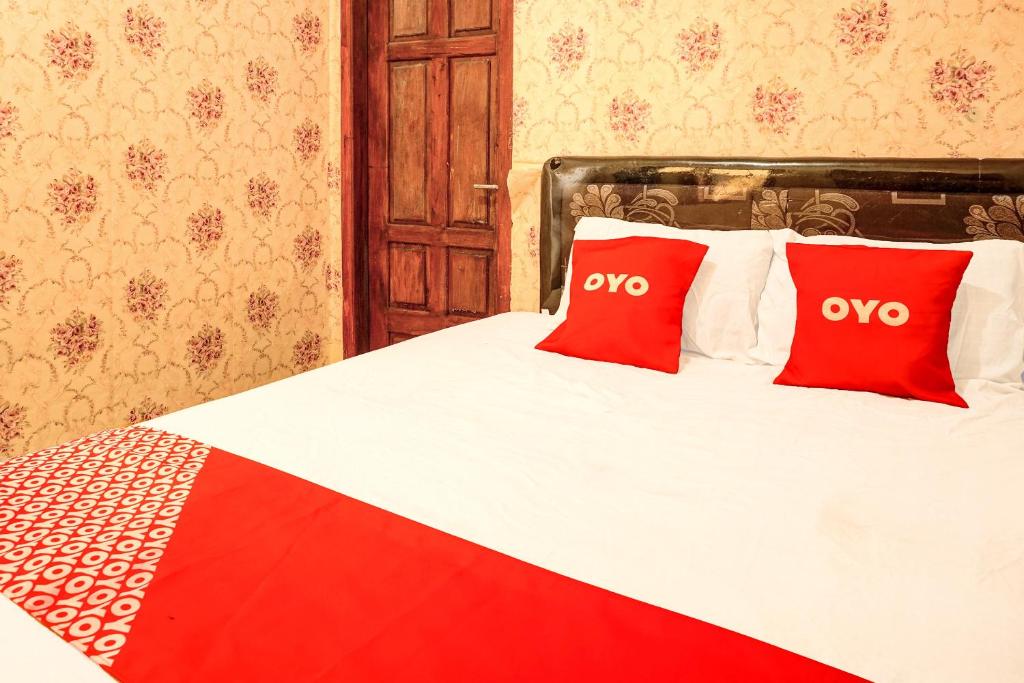 a bedroom with a bed with two red pillows at OYO Life 92499 Bagas Homestay Wonokitri in Pasuruan