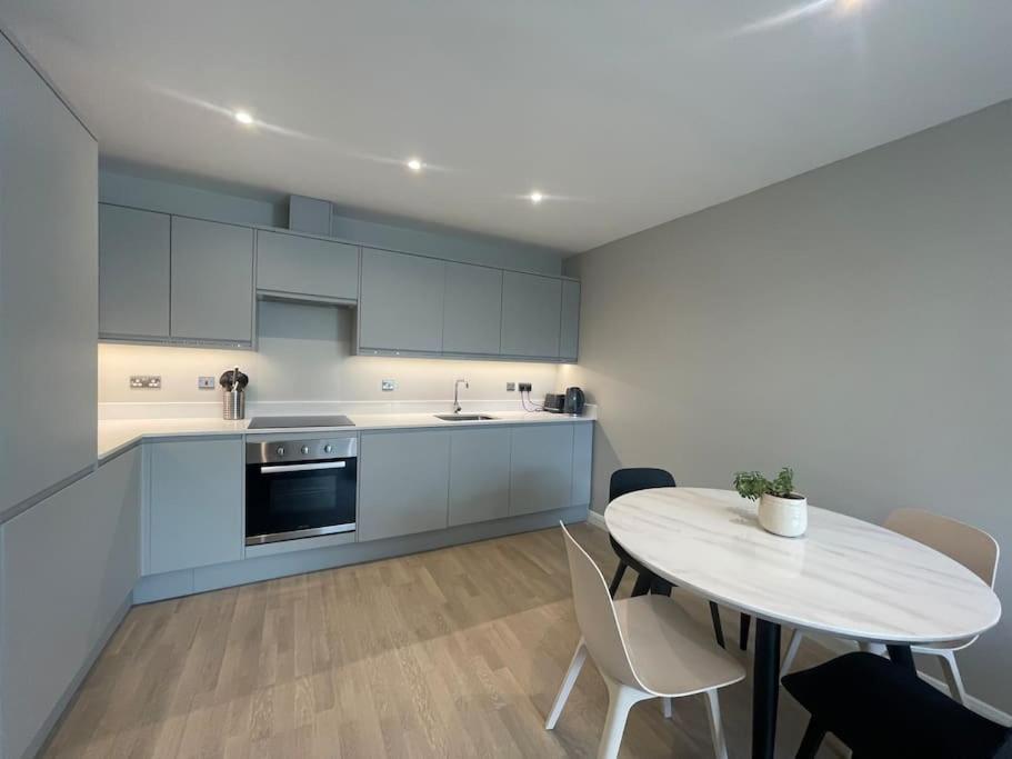 een keuken met een tafel en een tafel en stoelen bij Marvellous New Build 2 Bed Flat - 1 Ophelia Court in Epsom