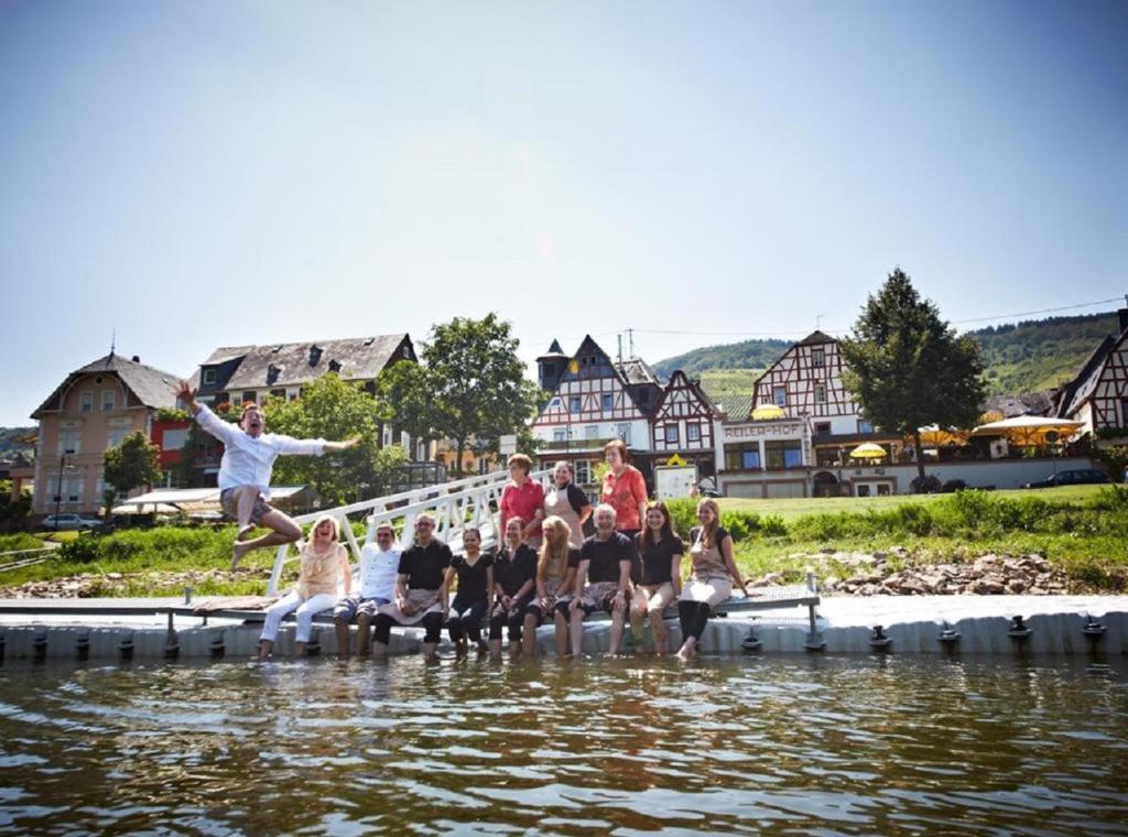 eine Gruppe von Menschen, die auf einem Dock im Wasser sitzen in der Unterkunft Hotel Reiler Hof in Reil