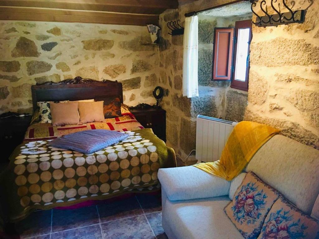 a bedroom with a bed and a couch in a room at Casa rural Buxo Ribeira Sacra in Carballedo