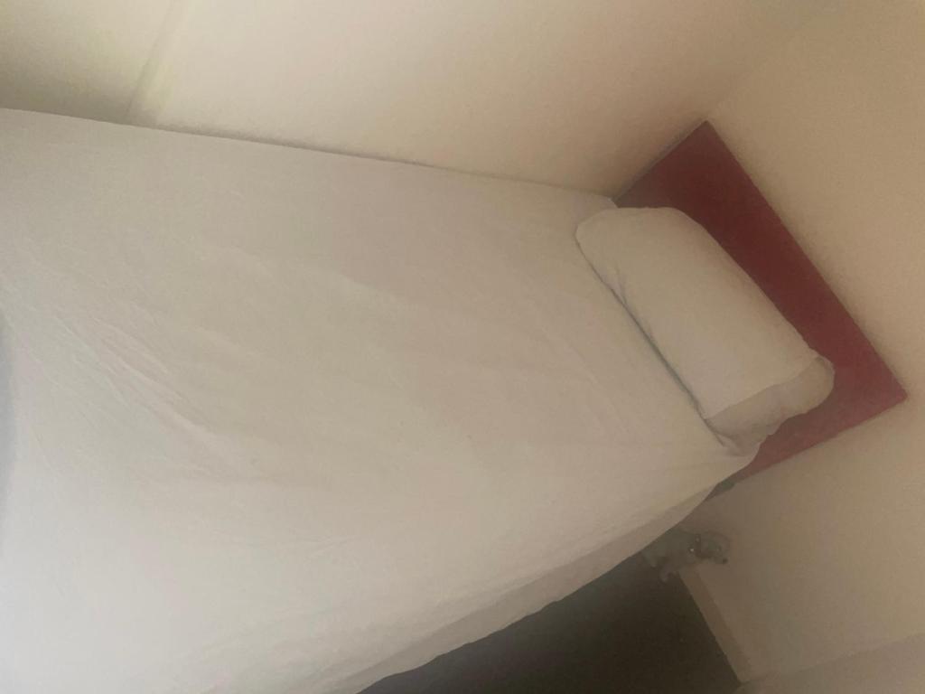 - un lit dans une petite chambre avec un oreiller blanc dans l'établissement Montrose Street, à Marton