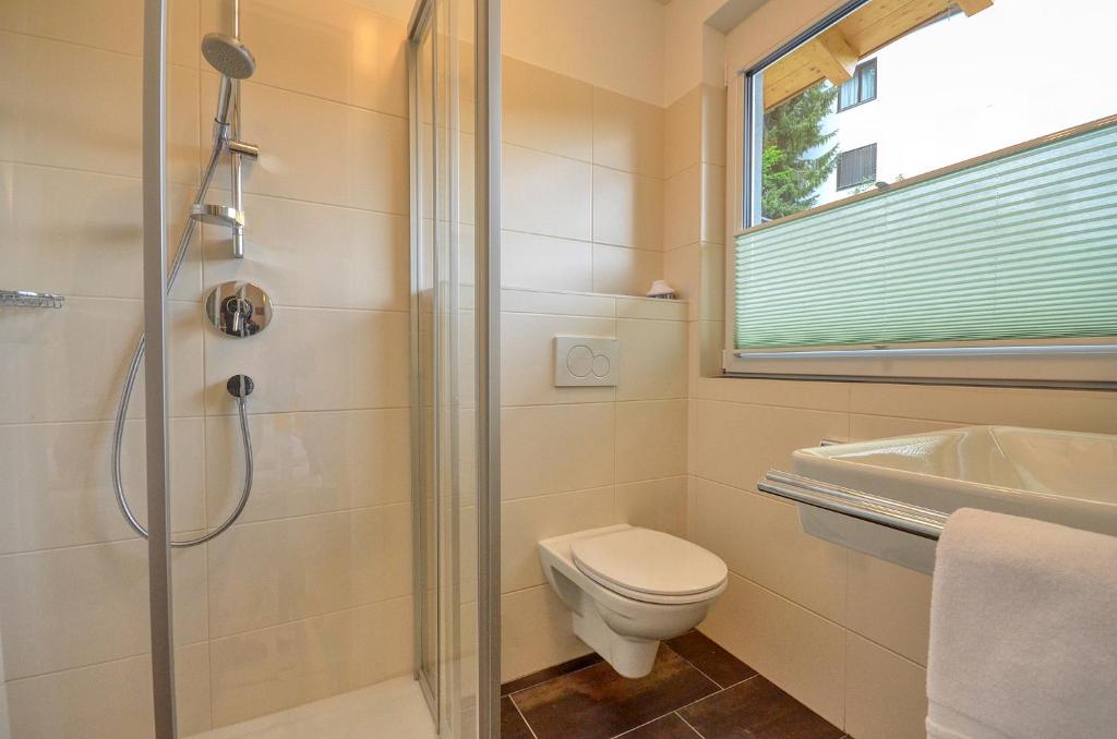 a bathroom with a shower and a toilet and a sink at Apartment Snowmountain - by Alpen Apartments in Zell am See