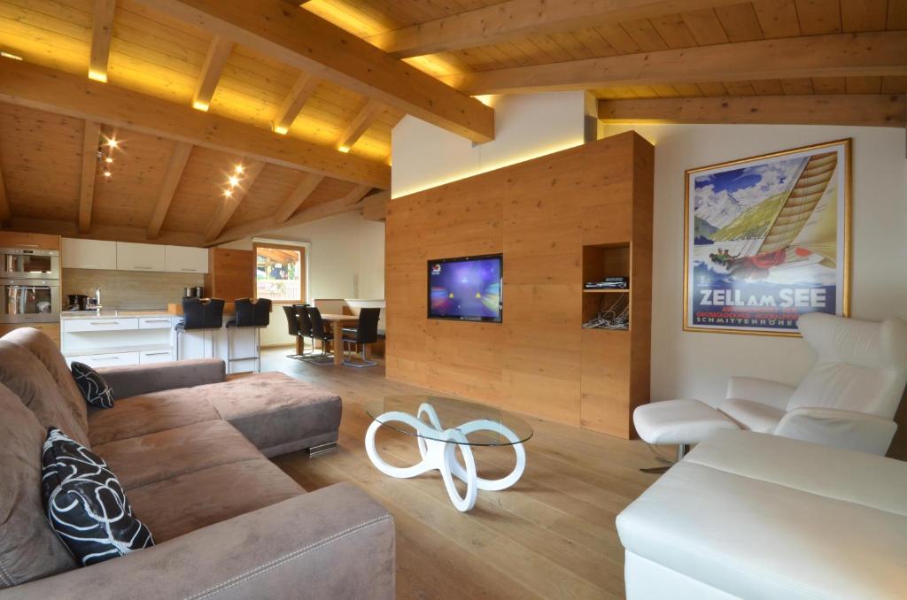 ein Wohnzimmer mit einem Sofa und einem Tisch sowie eine Küche in der Unterkunft Apartment Diana - by Alpen Apartments in Zell am See