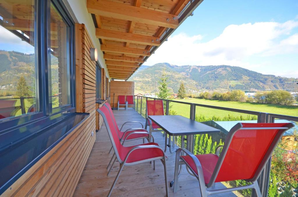 カプルーンにあるResidence Alpin - by Alpen Apartmentsの赤い椅子と景色を望むテーブル付きのポーチ
