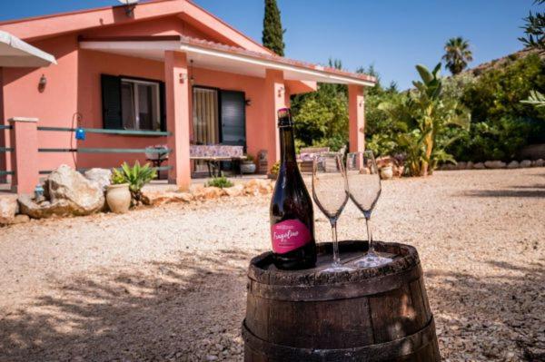 una botella de vino en un barril con dos copas de vino en Villa Agapanthus en Castellammare del Golfo