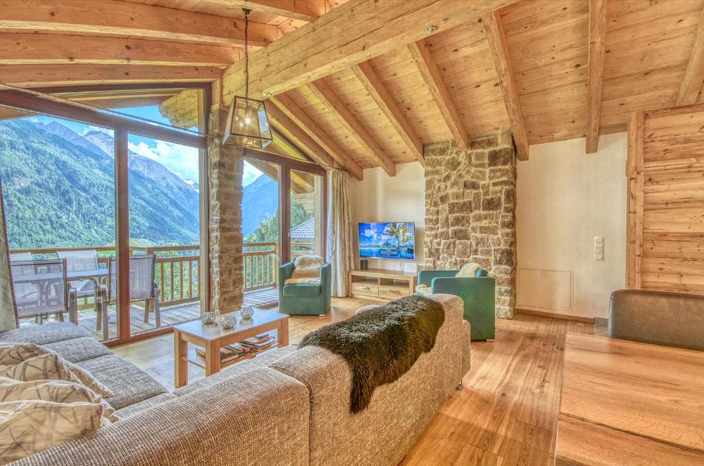 a living room with a couch and a television and mountains at Ski-in Ski-out Chalet Maiskogel 13A - by Alpen Apartments in Kaprun