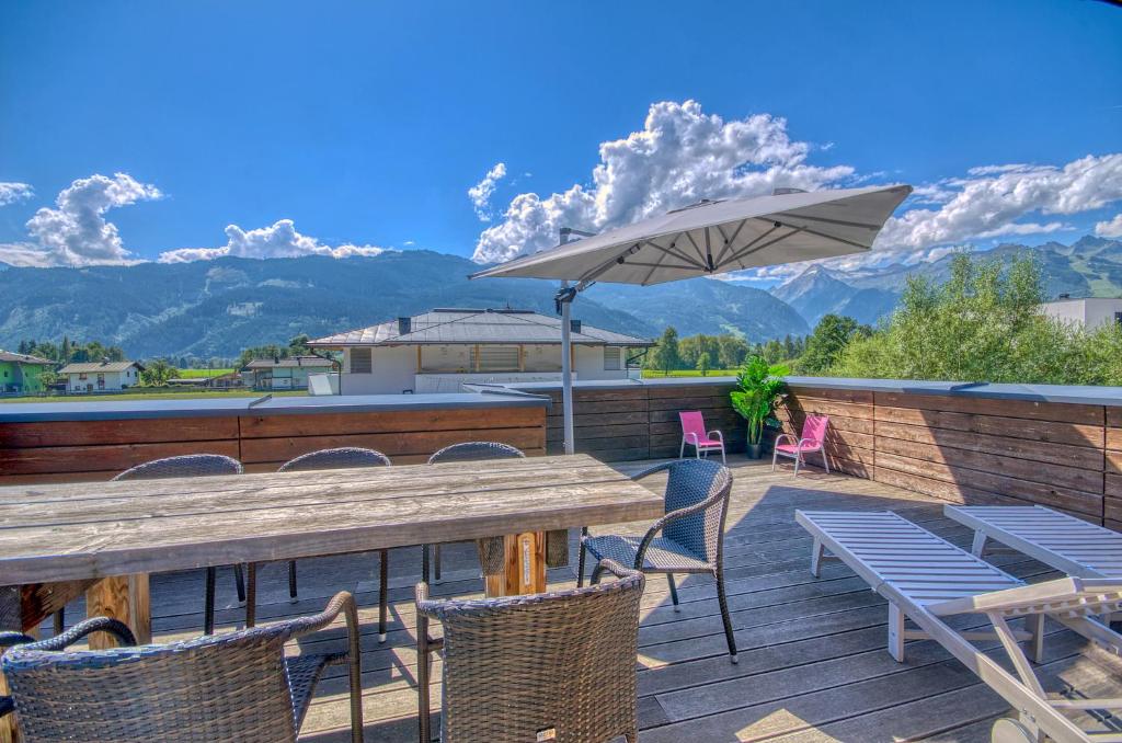 une table, des chaises et un parasol sur une terrasse dans l'établissement Gletscherblick 2 - by Alpen Apartments, à Zell am See