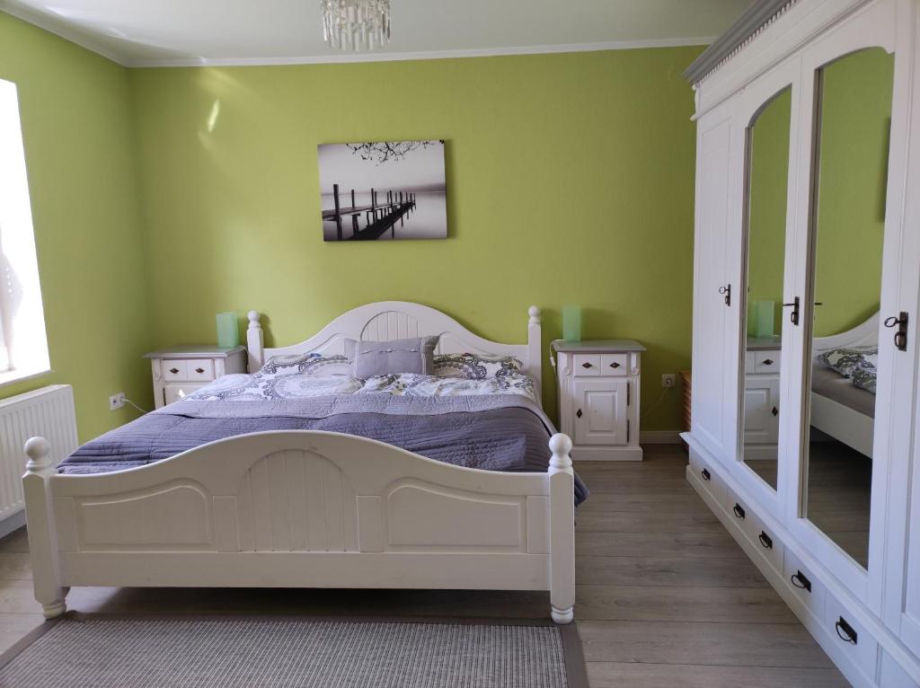 1 dormitorio con cama blanca y paredes verdes en Pier 12 Ferienwohnung, en Eckernförde
