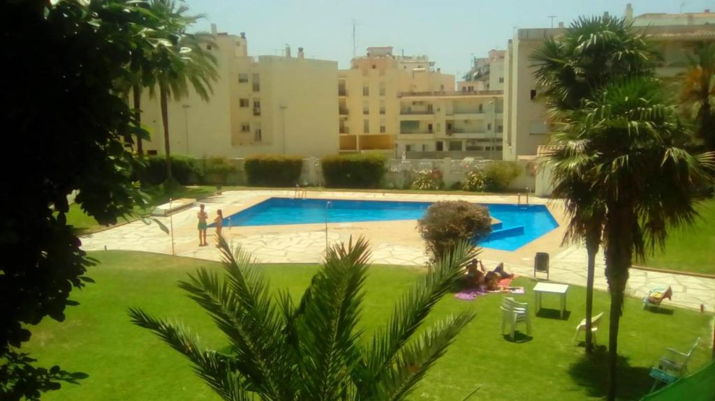 a view of a swimming pool with palm trees and buildings at Charming Studio Nerja with pool in Nerja