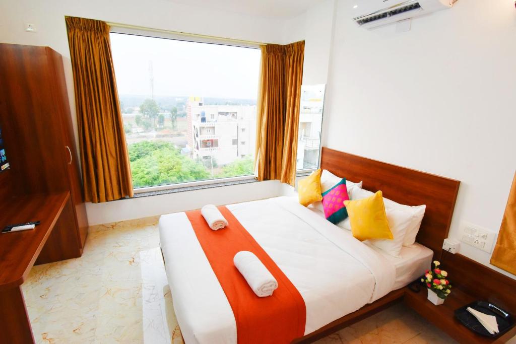 um quarto com uma cama e uma janela grande em Keerthis Royal Suites Kempegowda International Airport em Yelahanka