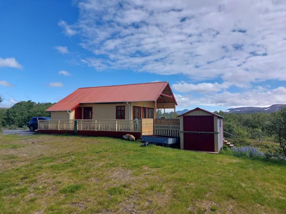 une maison avec un toit rouge sur une pelouse dans l'établissement Cosy cabin near Hraunfossar, à Reykholt