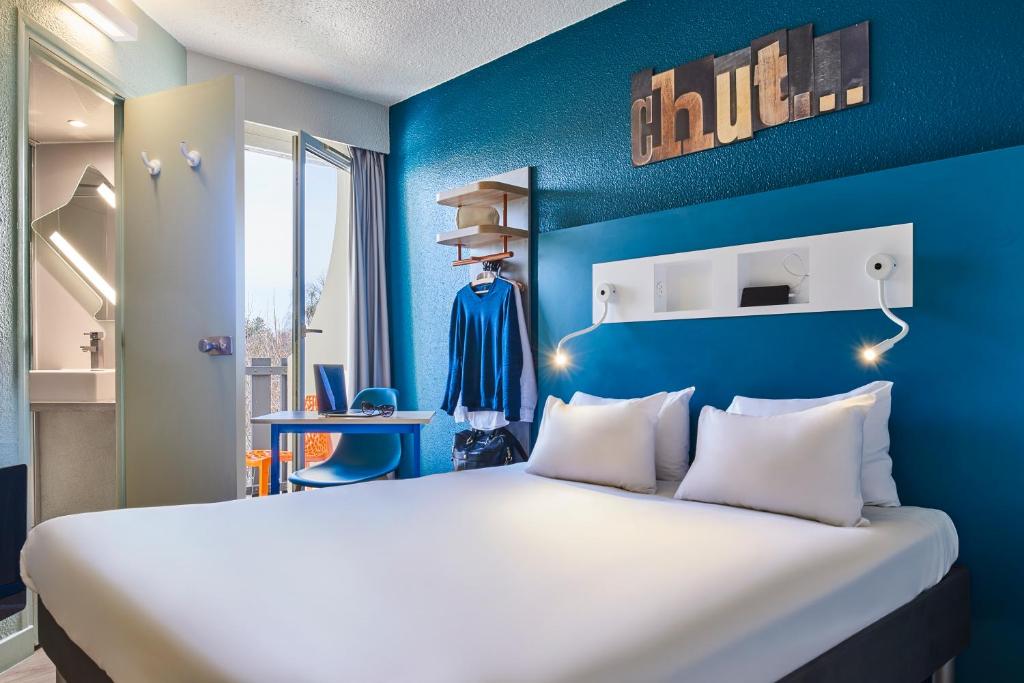 Cette chambre dispose d'un grand lit avec un mur bleu. dans l'établissement ibis budget Saint-Ouen-l'Aumône, à Saint-Ouen-lʼAumône