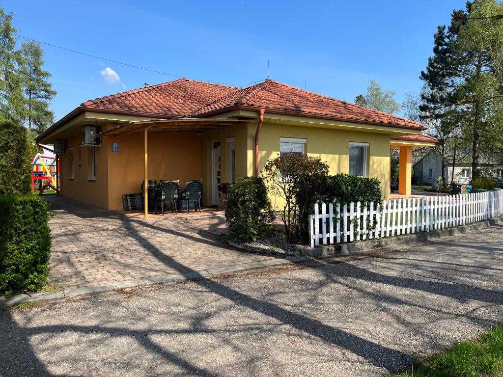 une petite maison jaune avec une clôture blanche dans l'établissement Villa Gracia Patince, à Patince