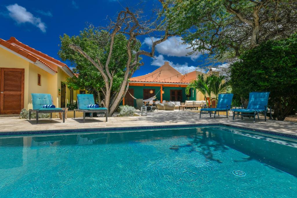 uma piscina com cadeiras azuis e uma casa em Villa Adelaida em Palm-Eagle Beach