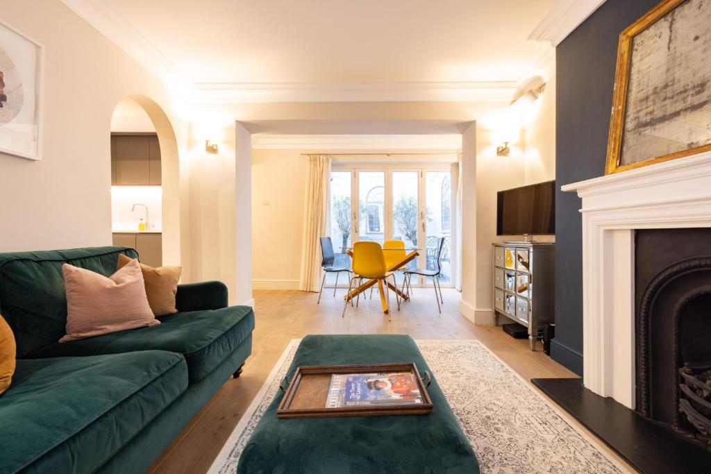 a living room with a green couch and a fireplace at The Brunswick Oasis in London