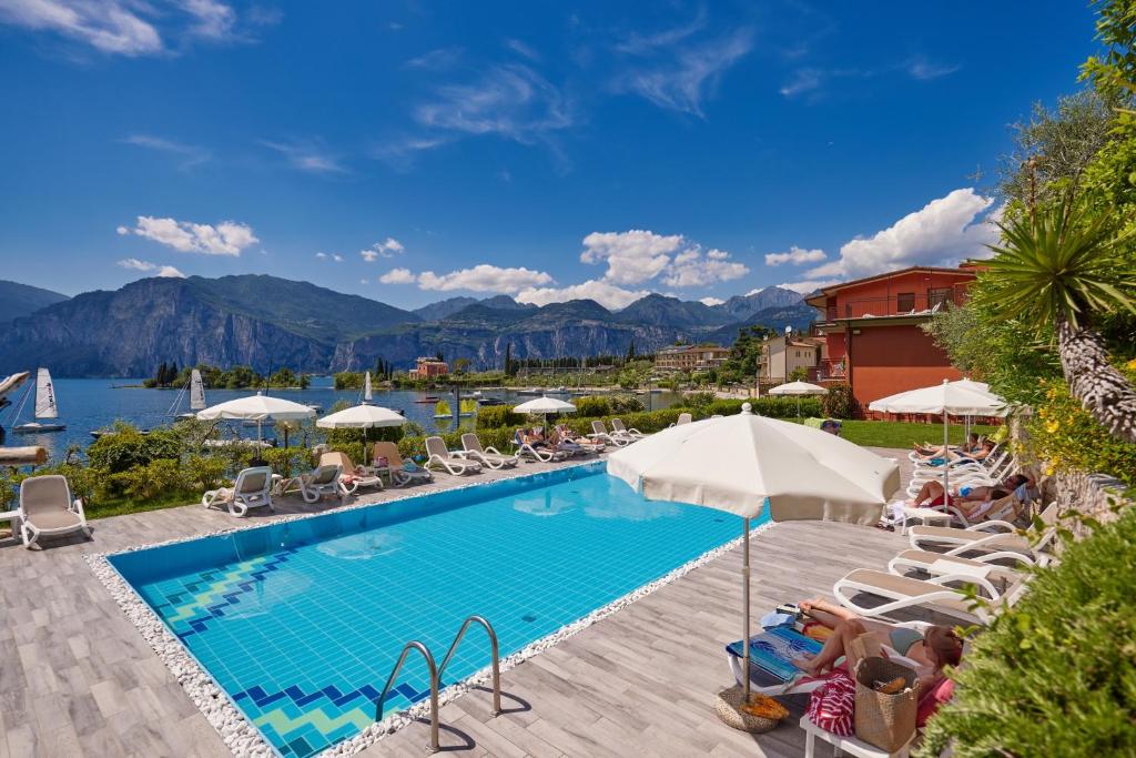 einen Pool in einem Hotel mit Stühlen und Sonnenschirmen in der Unterkunft Beach Hotel Rosa in Malcesine
