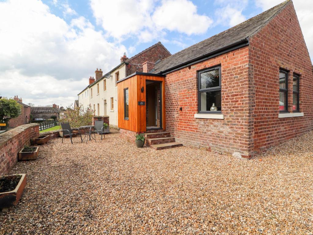 a brick house with an orange door on a gravel yard at The Flat in Carlisle