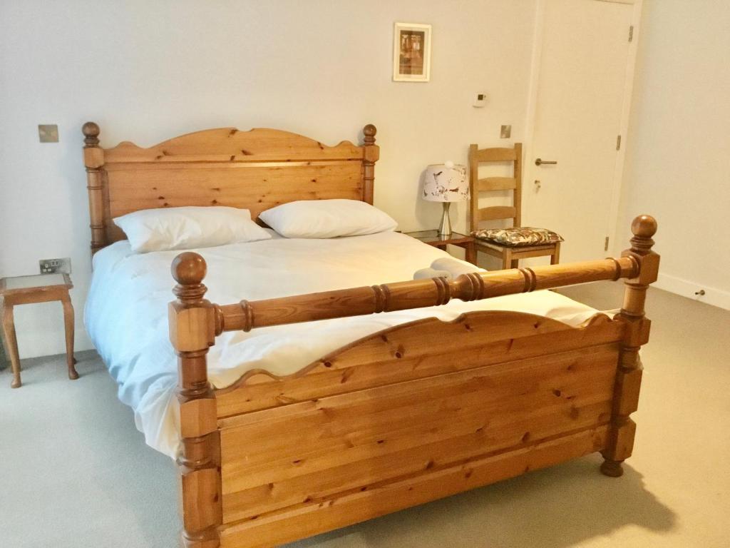 um quarto com uma cama de madeira com uma estrutura de madeira em Luxury Ensuite Room 2 Minutes from Cambridge Station em Cambridge