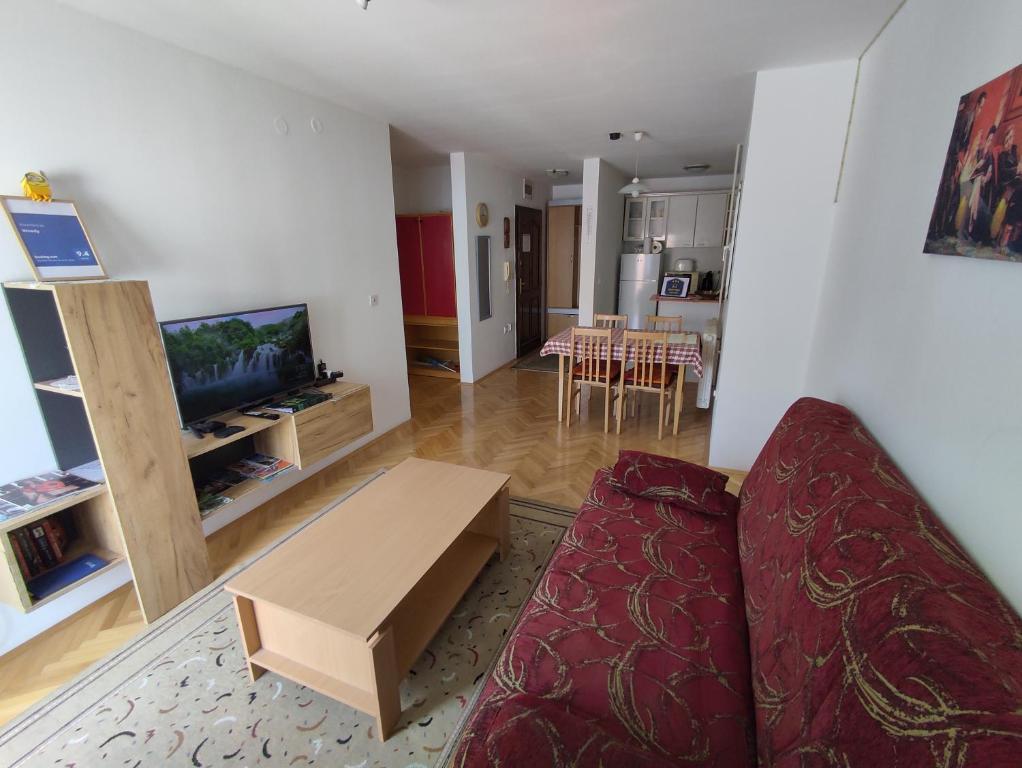 uma sala de estar com um sofá, uma televisão e uma mesa em Woody em Novi Sad
