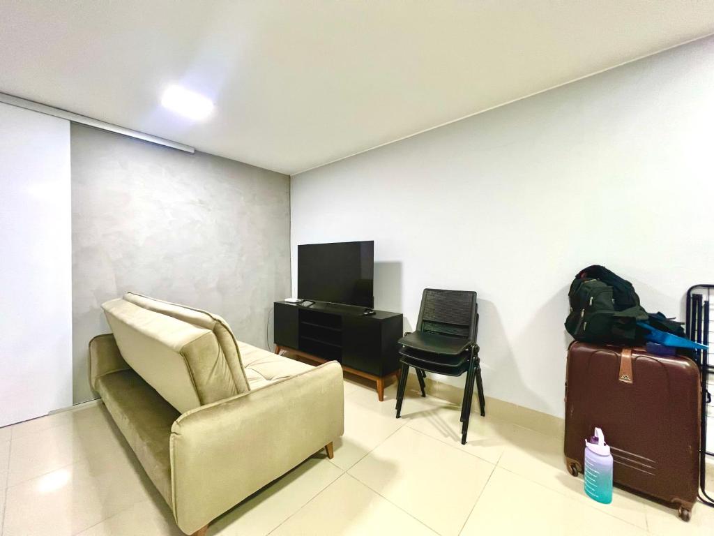 a living room with a couch and a television and a chair at Kit asa norte in Brasilia