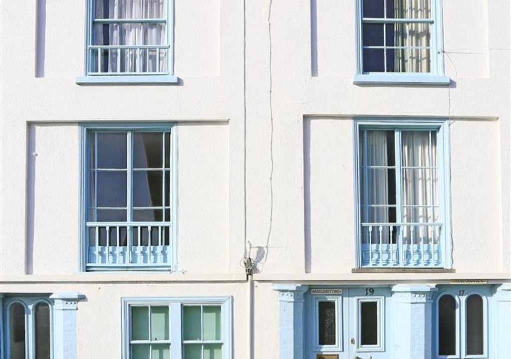ein weißes Gebäude mit blauen Fenstern in der Unterkunft Margaretting in Aldeburgh