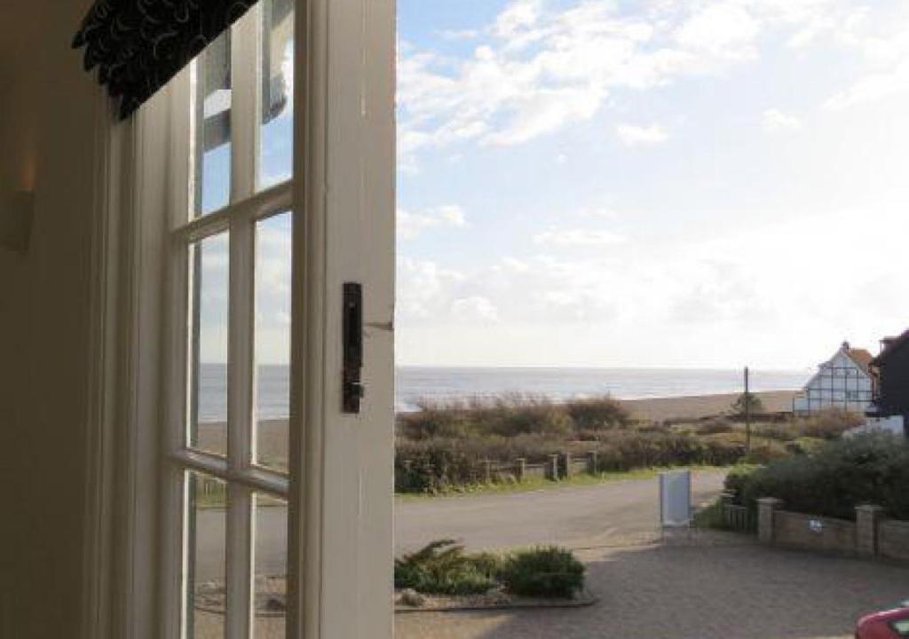 uma janela com vista para a praia a partir de uma casa em 2 Truman Lodge em Thorpeness
