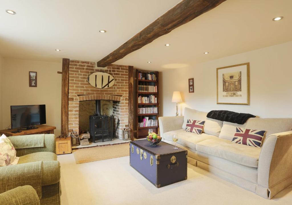 a living room with a couch and a fireplace at Walnut Tree Cottage in Mildenhall