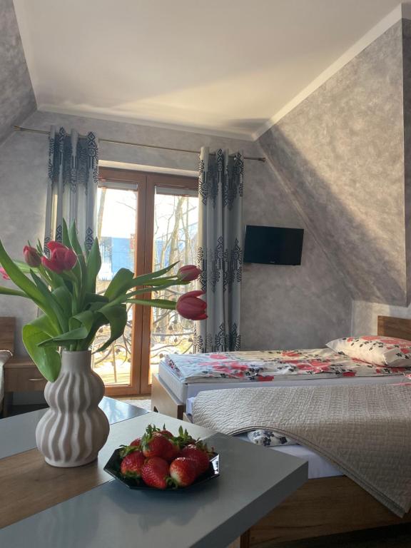a bedroom with a table with a vase of flowers and a plate of fruit at Witowiański Dworek in Witów