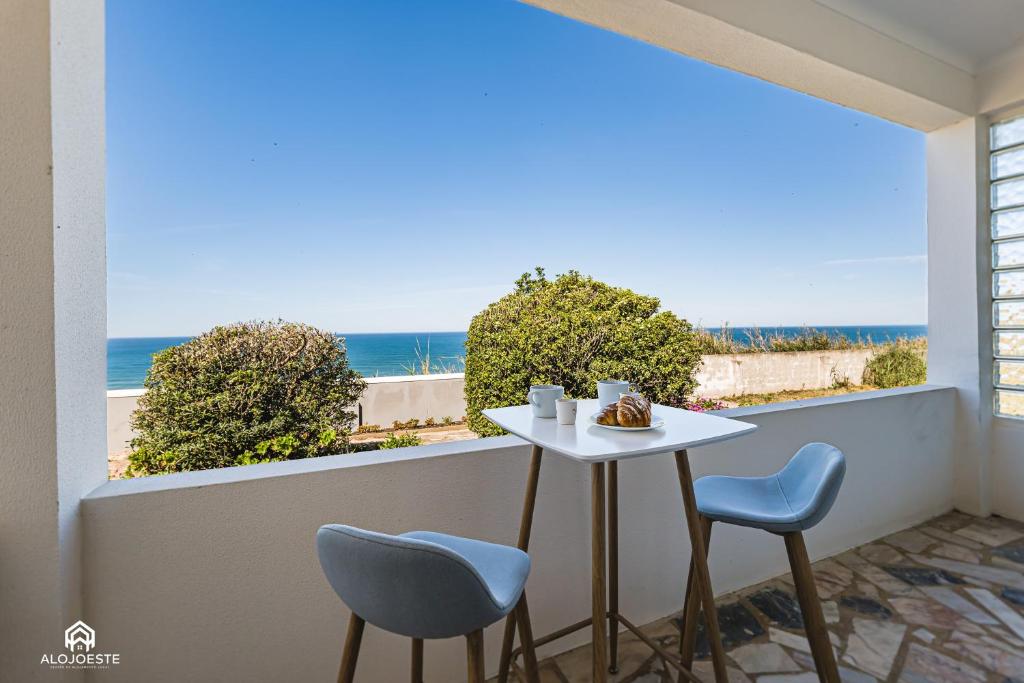 balcón con mesa y sillas y la playa en Casa à Beira Mar - Countryhouse with Ocean view, en São Pedro da Cadeira