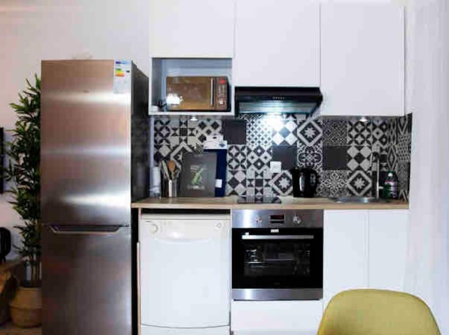 a kitchen with a stainless steel refrigerator and a stove at APPARTEMENT COSY Balcon à 30min de PARIS in Cergy