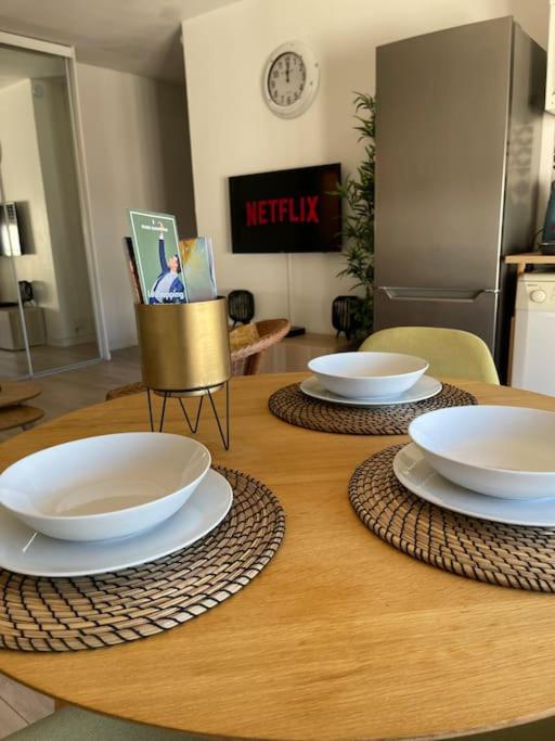 a wooden table with two white bowls on top of it at APPARTEMENT COSY Balcon à 30min de PARIS in Cergy